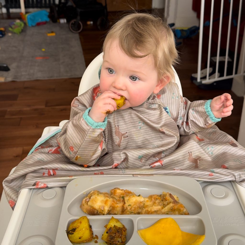 10 month old baby eating bread squares soaked in lentil soup