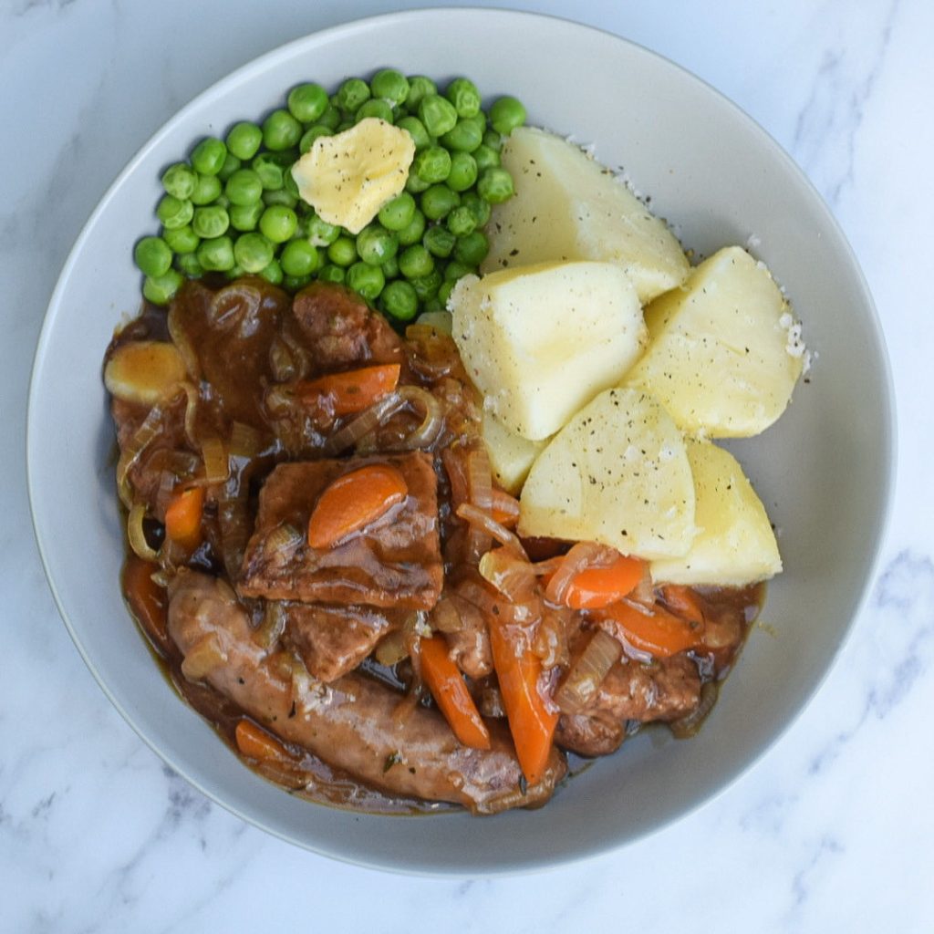 stewed sausages with boiled potatoes and peas in a bowl