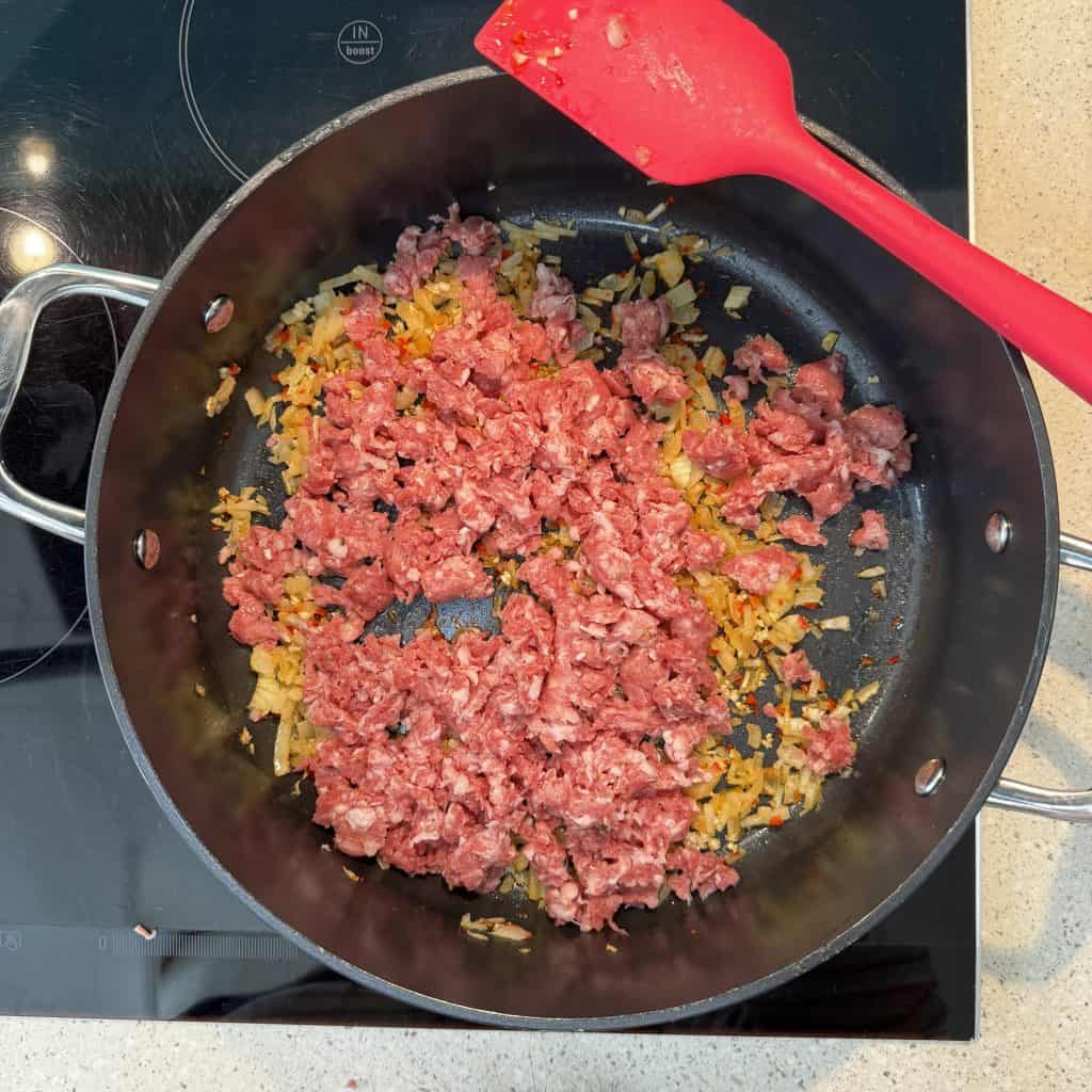 Italian sausage broken up in pan with garlic, chilli and onion