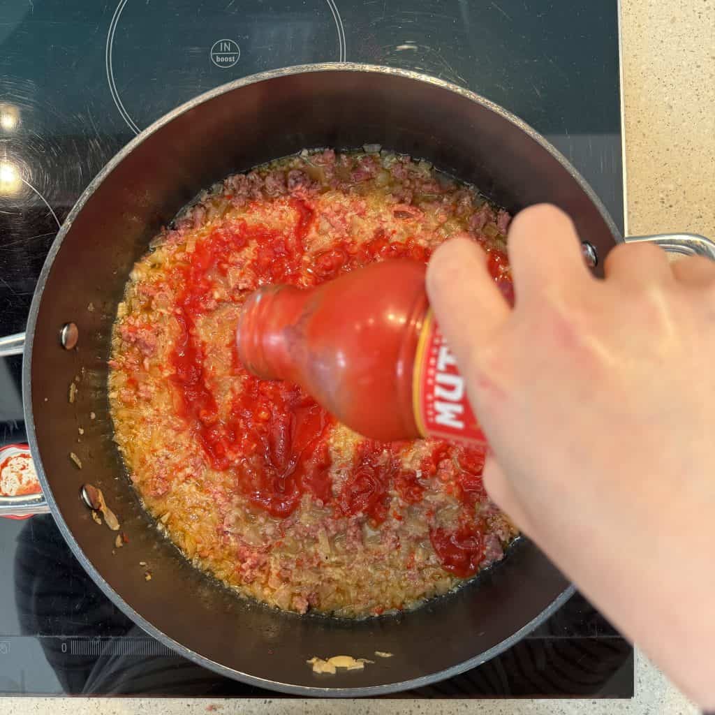 adding tomato pasatta to pan with Italian sausage and prosecco