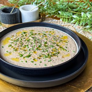 mushroom soup filling a black plate with truffle oil and chives for garnish