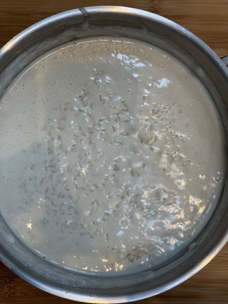 A close-up of a pot filled with creamy rice pudding, showing a thick, milky texture with visible grains of rice throughout the mixture.