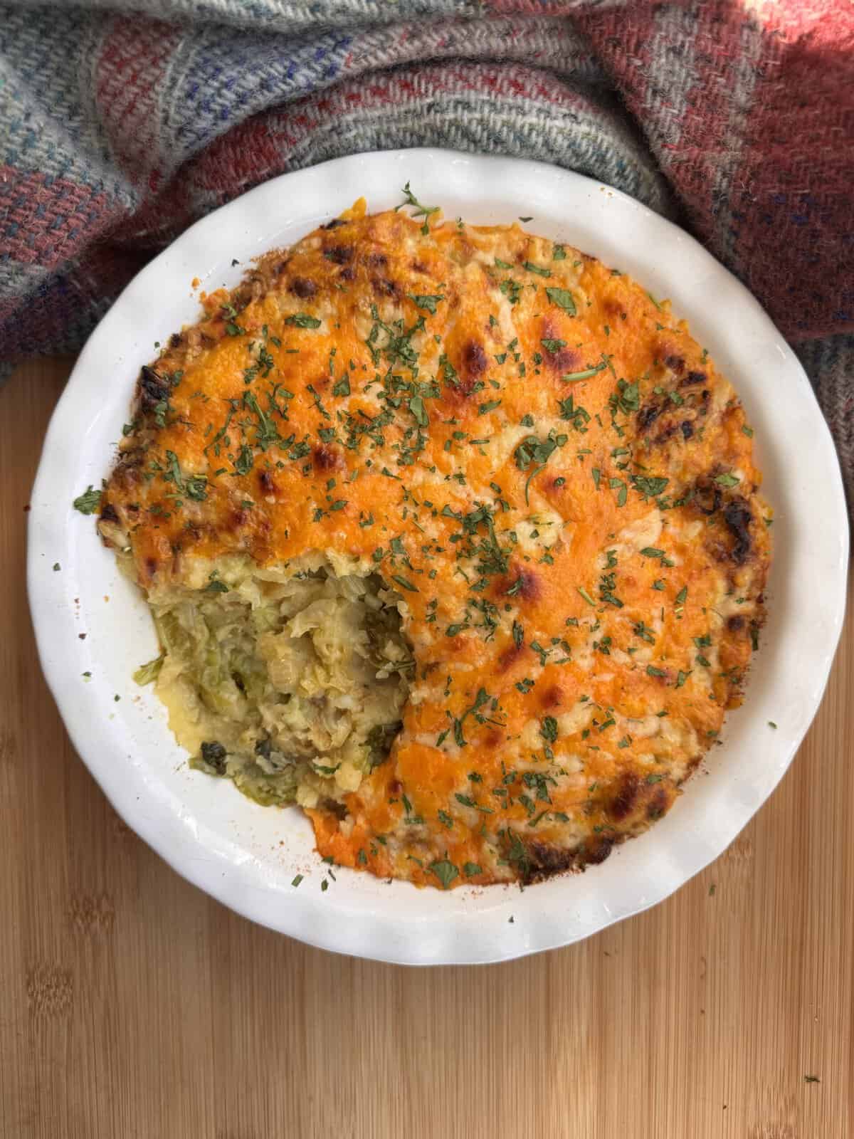 Delicious rumbledethumps with herbs, served in a white dish.