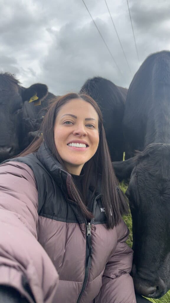 laurenscravings in a padded gilet takes a selfie with two black cows in a field.