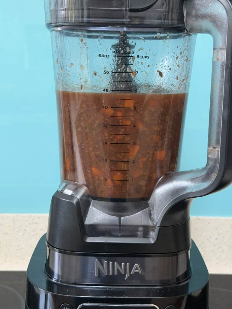 Ninja blender jug filled with a chunky, reddish-brown vegetable mixture.