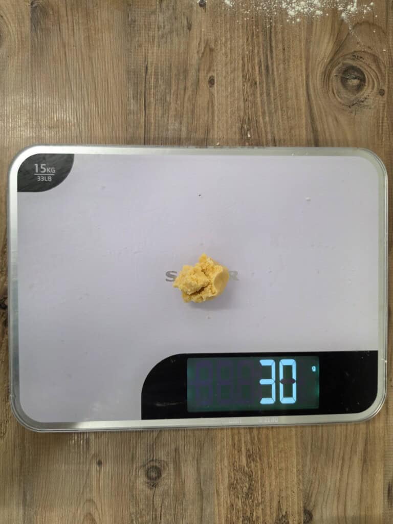 A small lump of dough on a digital kitchen scale showing a weight of 30 grams.