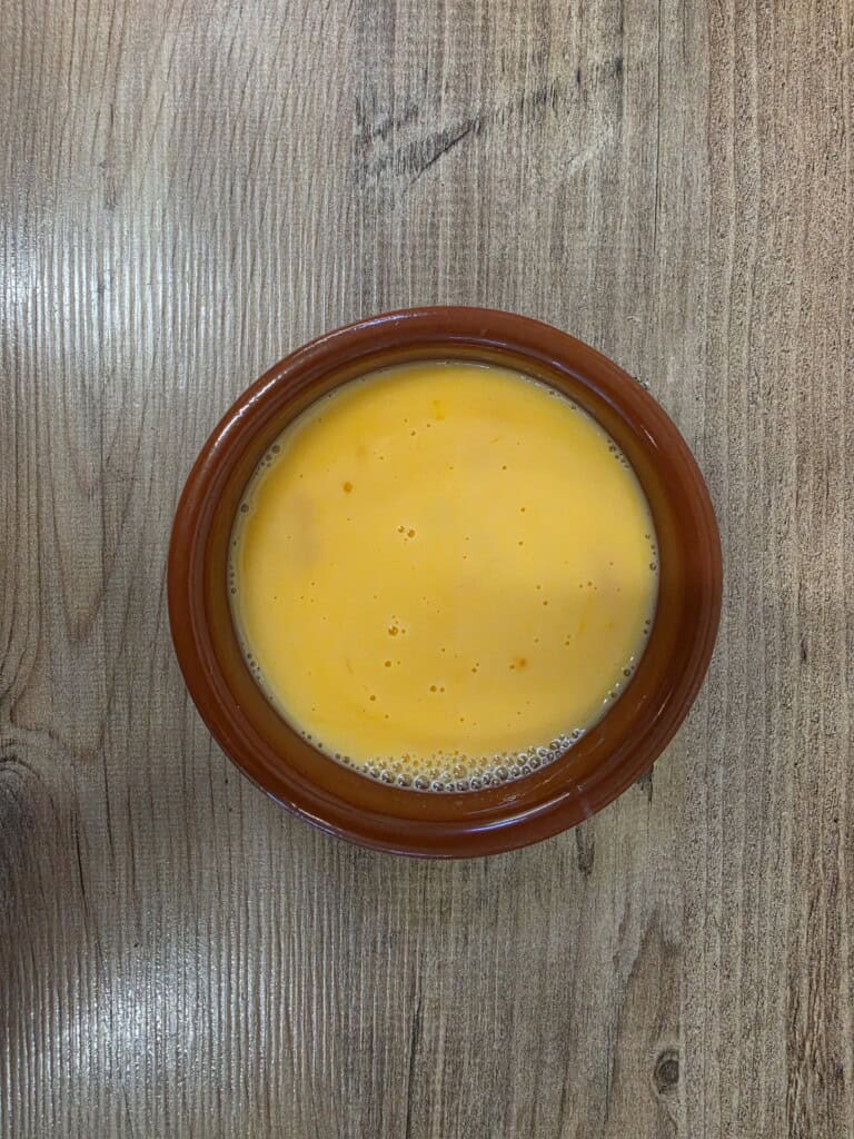 A brown ceramic bowl filled with a smooth, yellow custard or egg mixture.